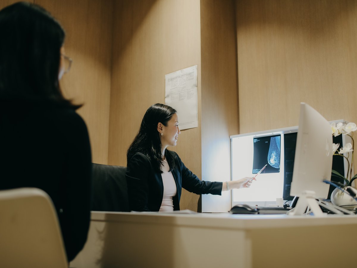 A specialist showing breast imaging on screen — mammography review with the patient.